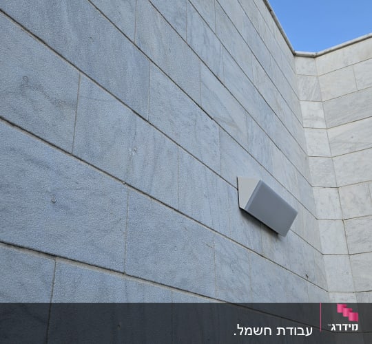 קיר עם תאורה חיצונית על רקע שמיים כחולים